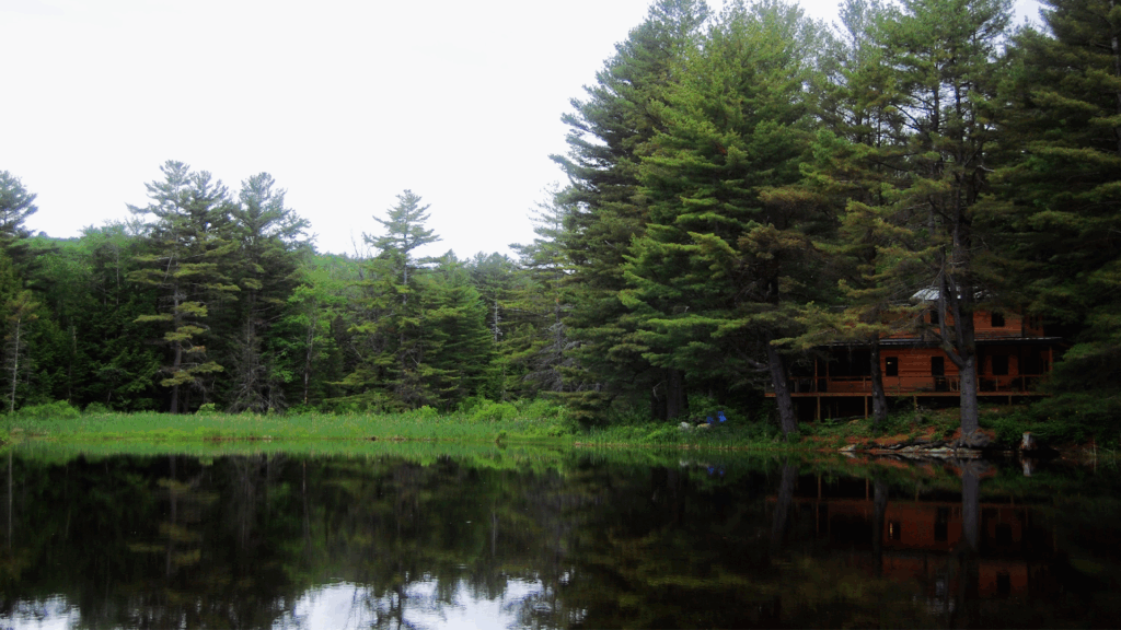 View of house from the street across the large pond nestled in the woods